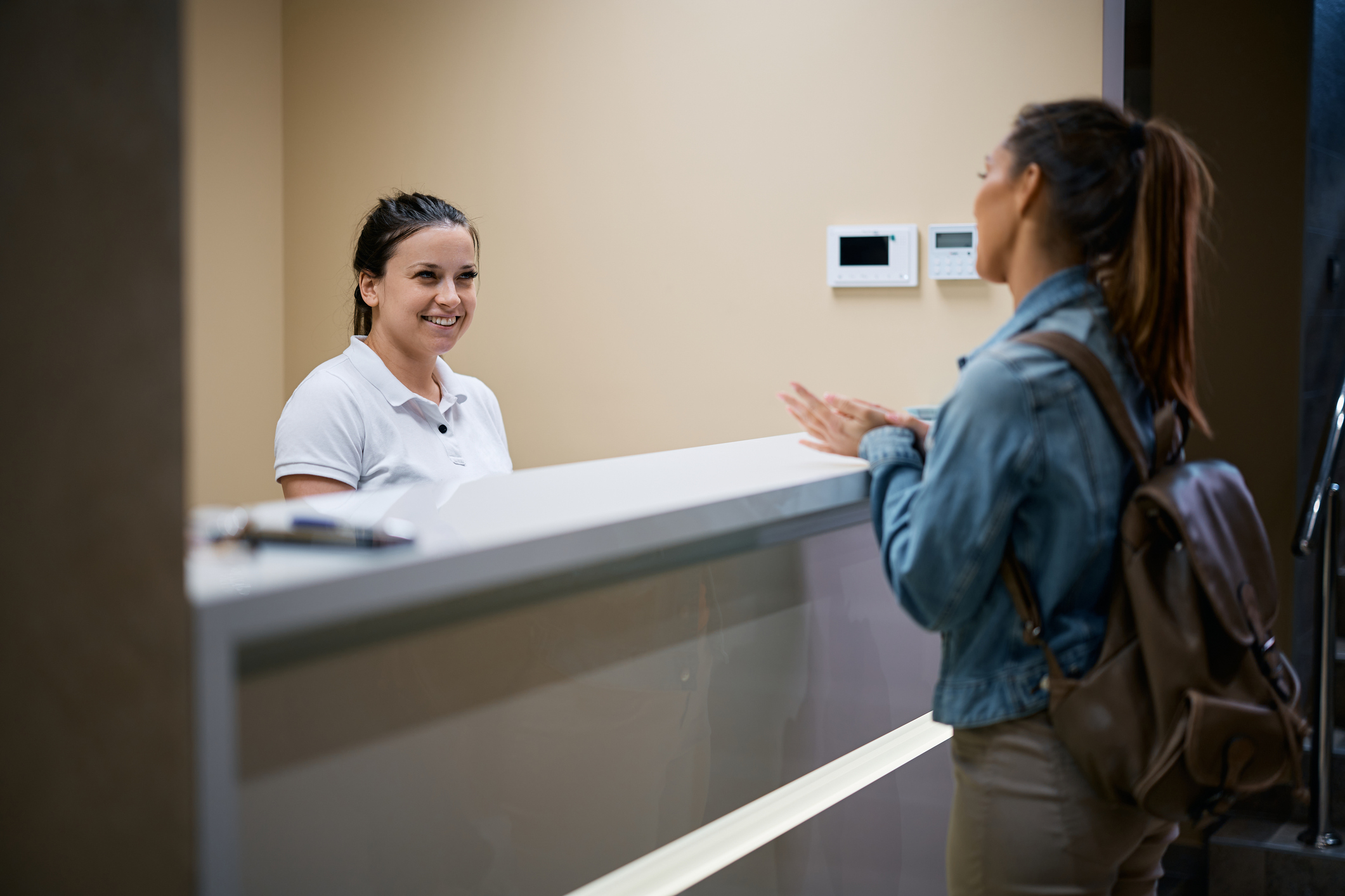 Happy receptions talking to a woman who is checking in at physical therapy center.