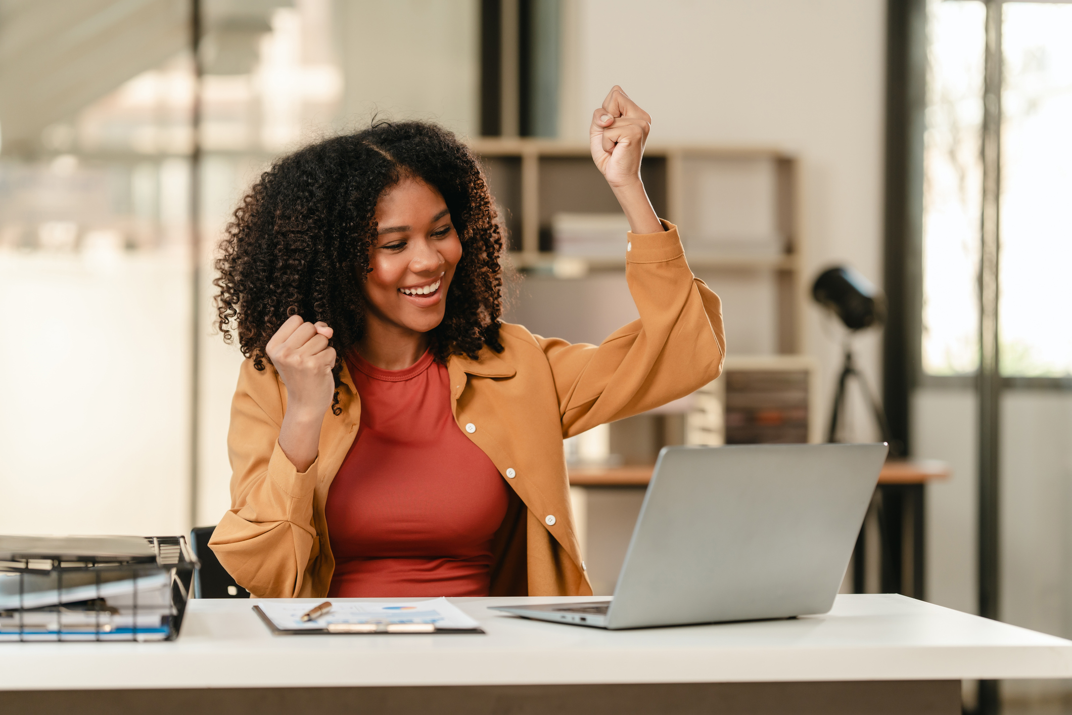 smiling African American university student with an afro hairstyle, holding a tablet and sitting at a desk with a laptop. online class learning from video conference